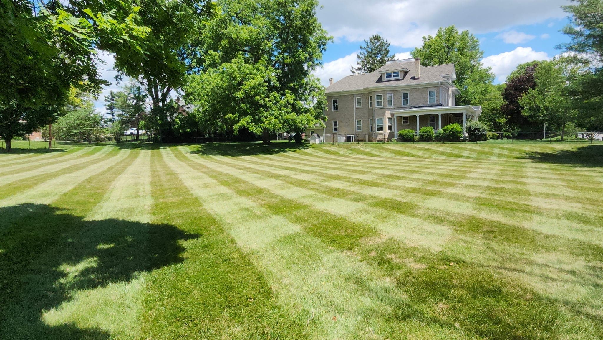 A freshly mown and striped lawn in front of a brick house